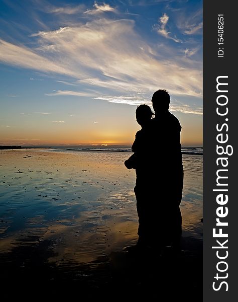 Young couple holding each other on a romantic beach at twilight