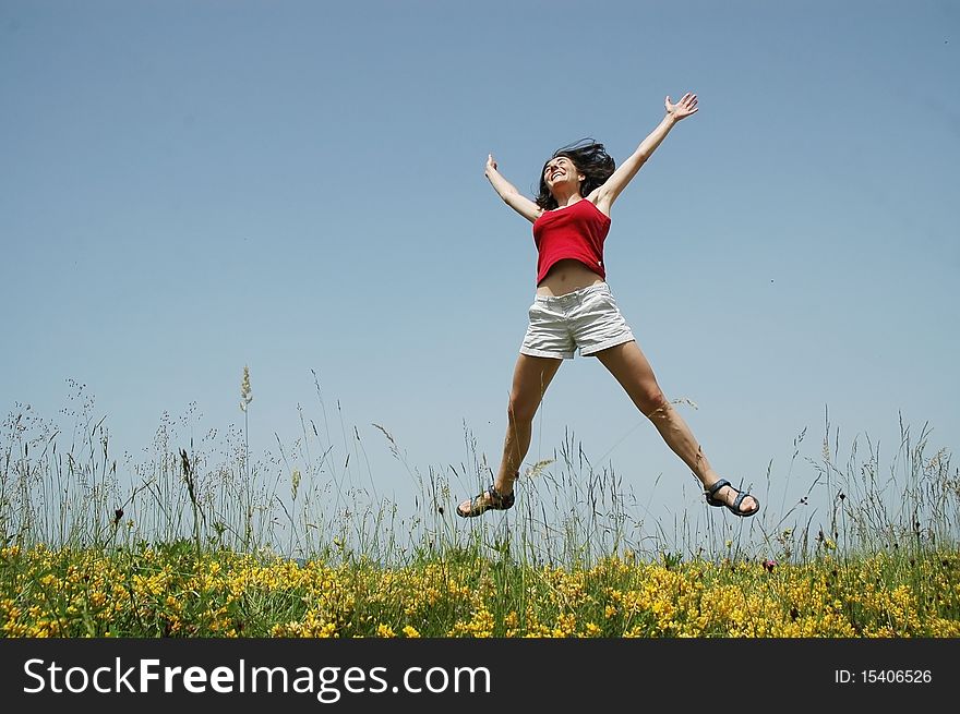 Beautiful young woman jumping in a meadow with yellow flowers