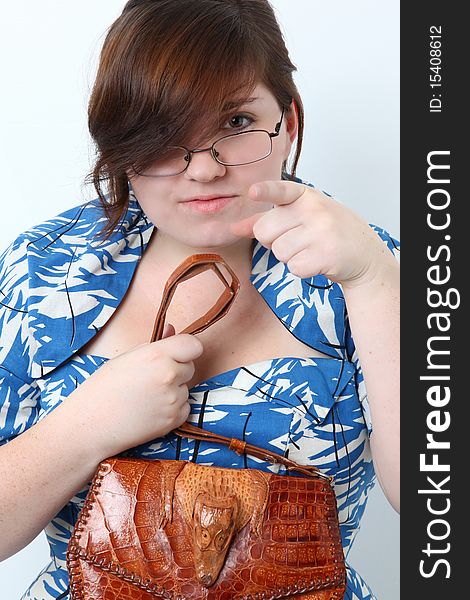 Young woman dressed in retro dress with alligator purse and glasses pointing at camera. Young woman dressed in retro dress with alligator purse and glasses pointing at camera.