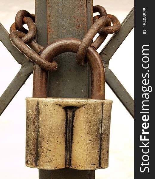 The old padlock and rusty chain on a metal lattice.