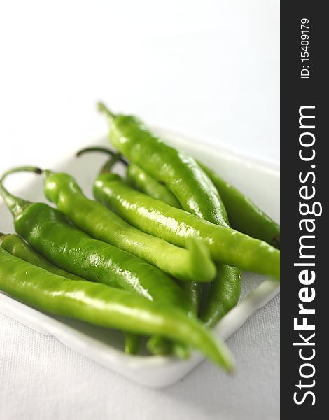 Green chilis in foam tray on white. Green chilis in foam tray on white