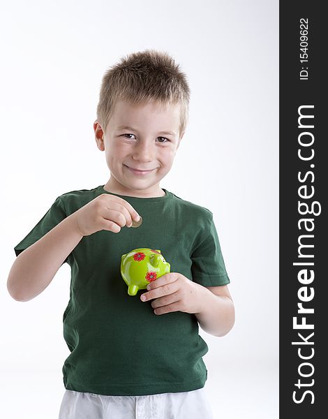 Little boy depositing money in his piggy bank.