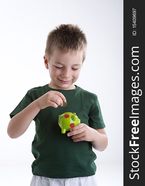 Little boy depositing money in his piggy bank.