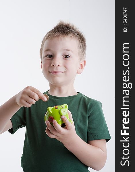 Little Boy Depositing Money In His Piggy Bank.