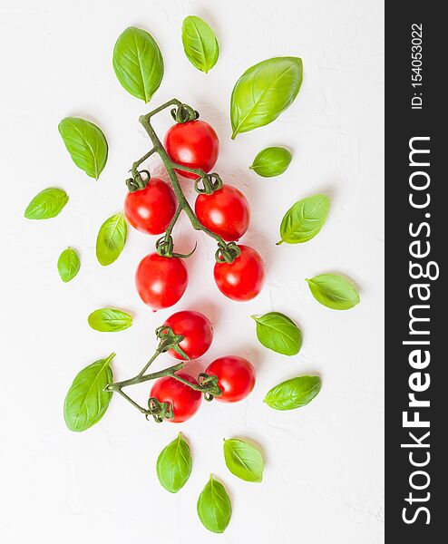 Organic Cherry Sugardrop Tomatoes on the Vine with basil and pepper on white kitchen background