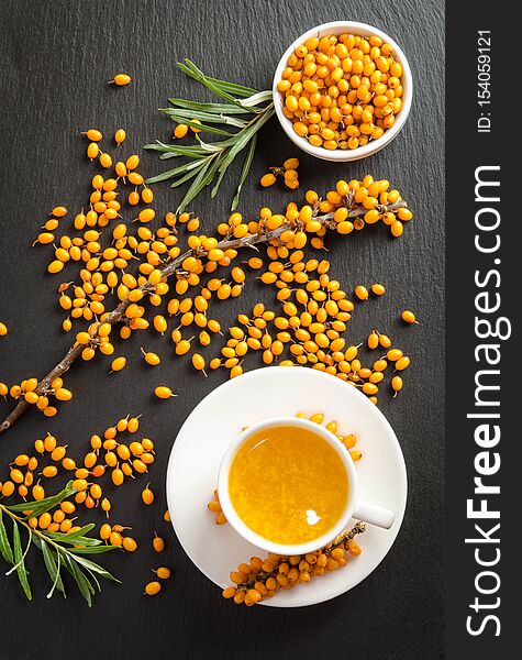 Sea buckthorn and cup of  tea on black stone table