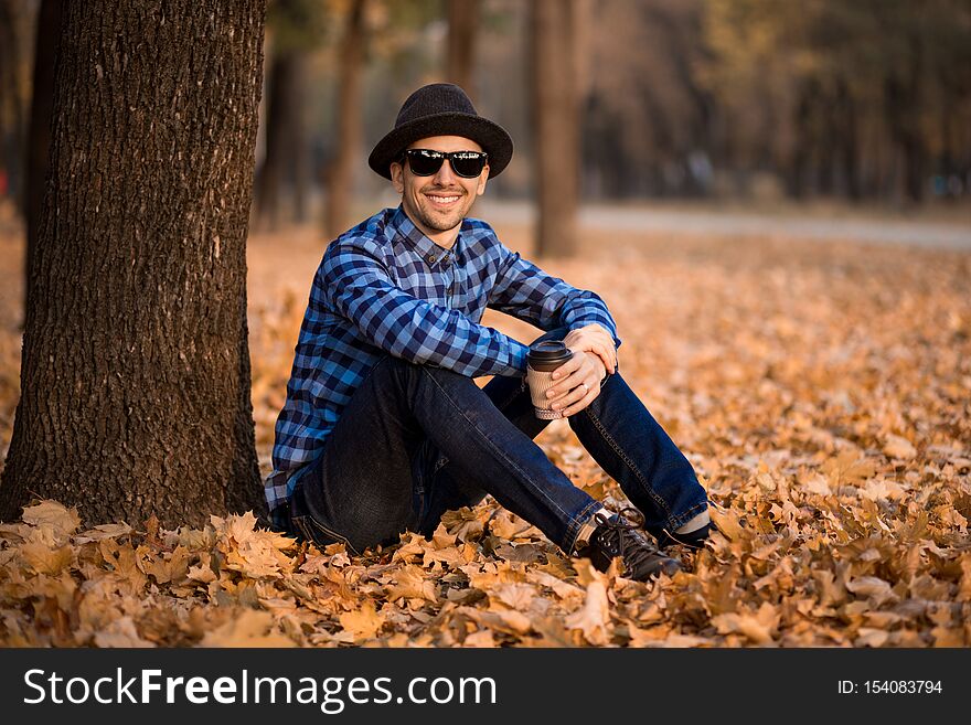 Young man wearing a check shirt and jeans walk in fall day