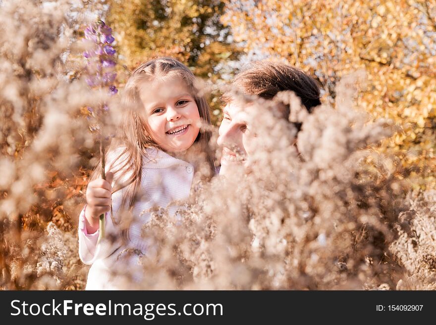 Happy dad and daughter posing among autumn yellow dry plants