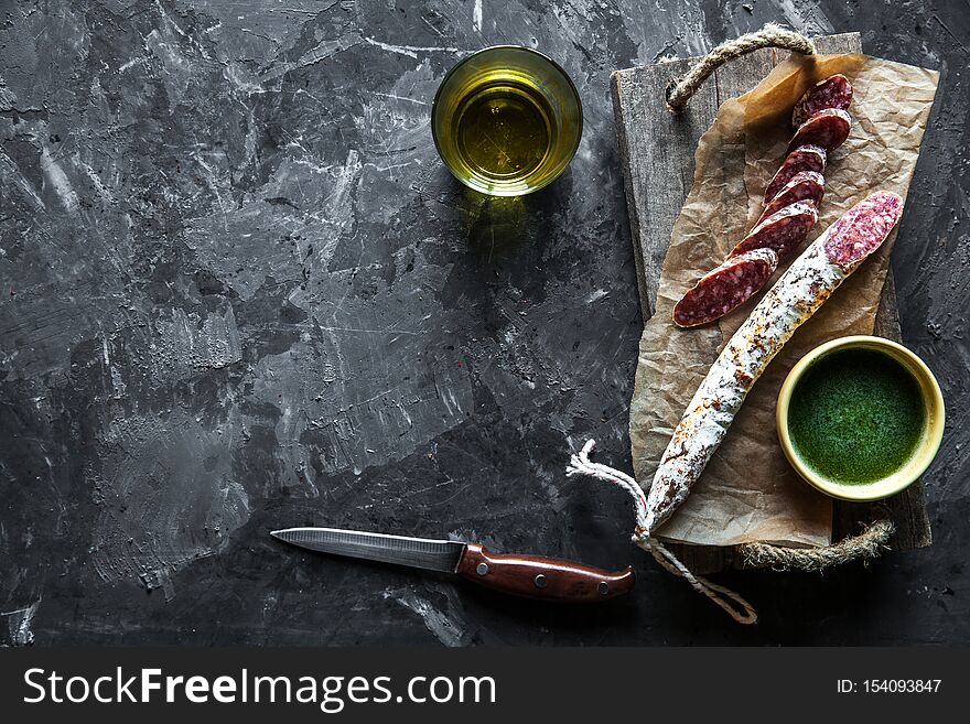 Sausage On A Dark Background With Elements Of Cooking. Cucumber, Onion, Ketchup