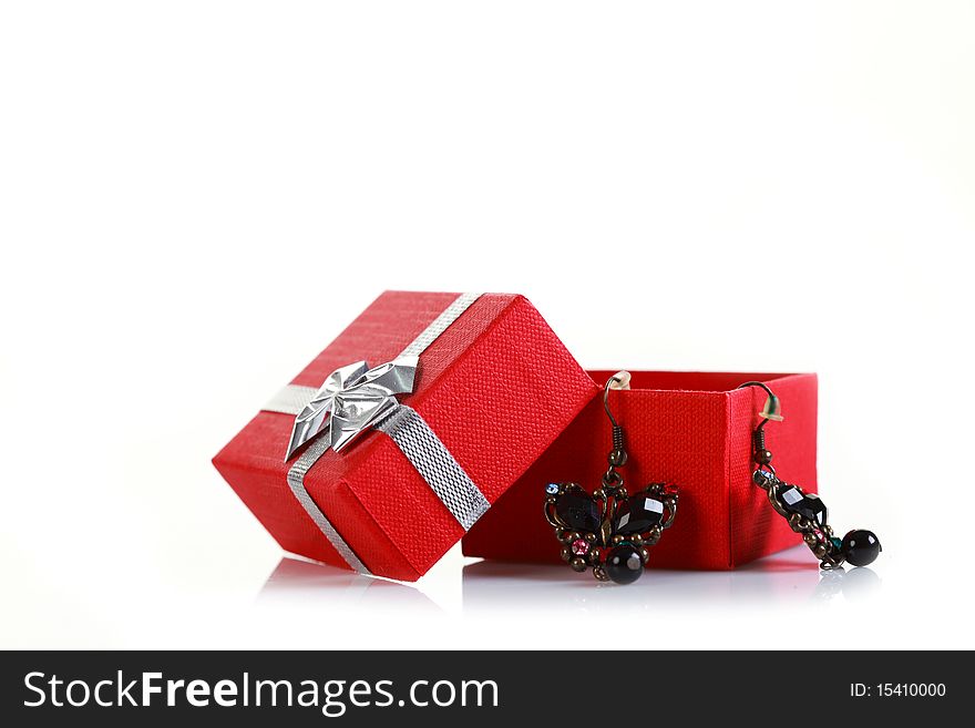 Butterfly earrings hanging out of a red gift box isolated on white