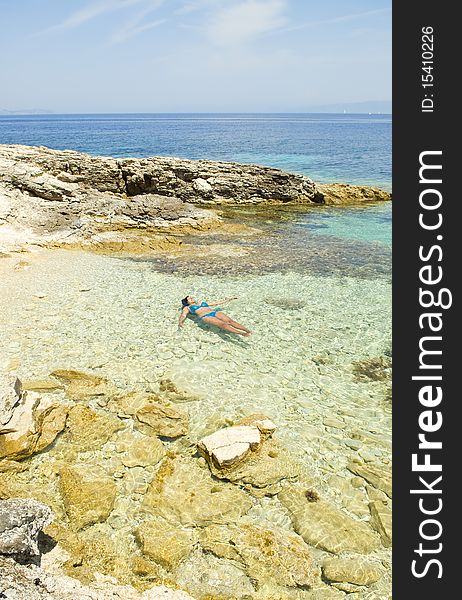 A color portrait photo of a beautiful asian woman floating in the sea in Paxos Greece. A color portrait photo of a beautiful asian woman floating in the sea in Paxos Greece.