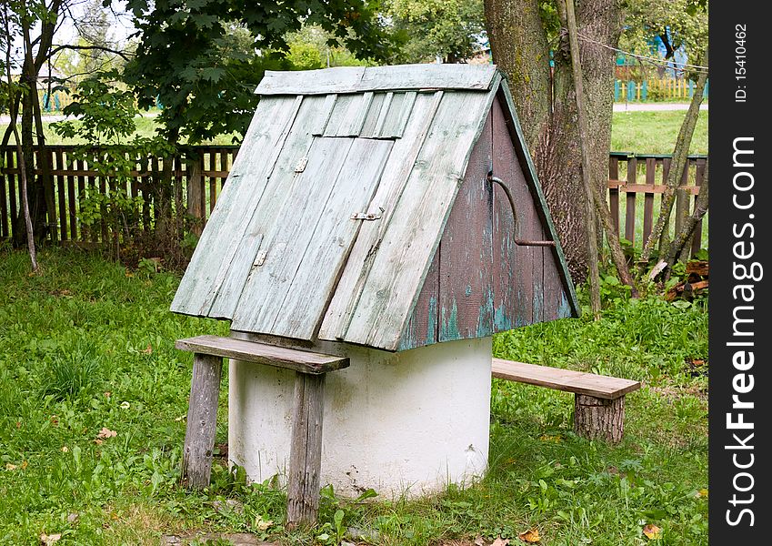 Old shabby well in a court yard of the rural house with benches for buckets. Old shabby well in a court yard of the rural house with benches for buckets