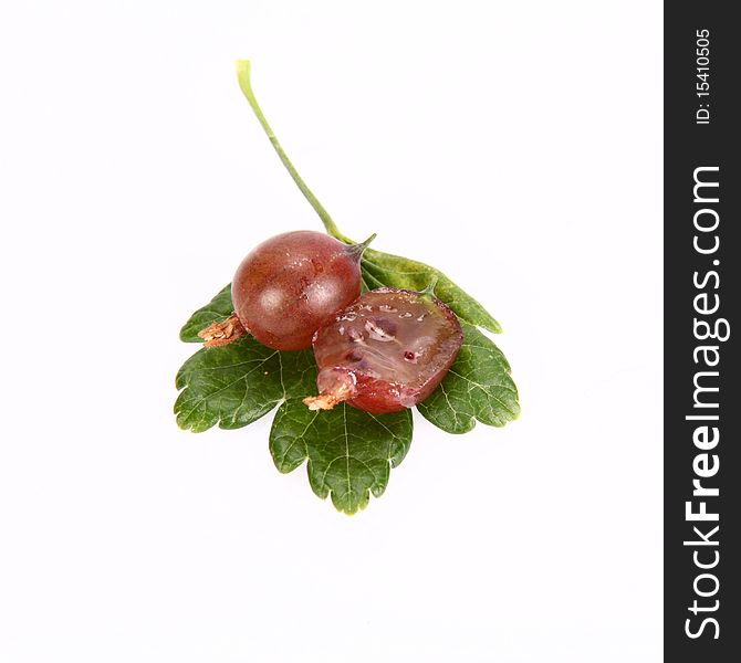 Red gooseberries, one cut in half, on a leaf on white background