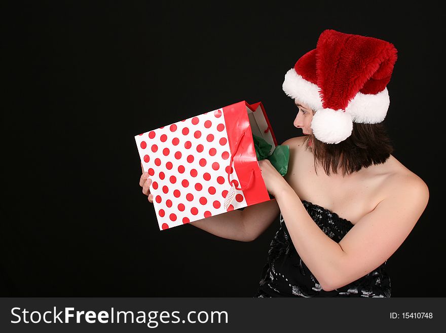 Beautiful brunette female wearing a christmas hat surprized at her gift. Beautiful brunette female wearing a christmas hat surprized at her gift