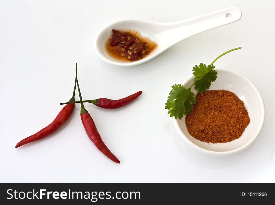 Chillis, chilli powder and chilli from a jar presented on white china against a white background. Chillis, chilli powder and chilli from a jar presented on white china against a white background