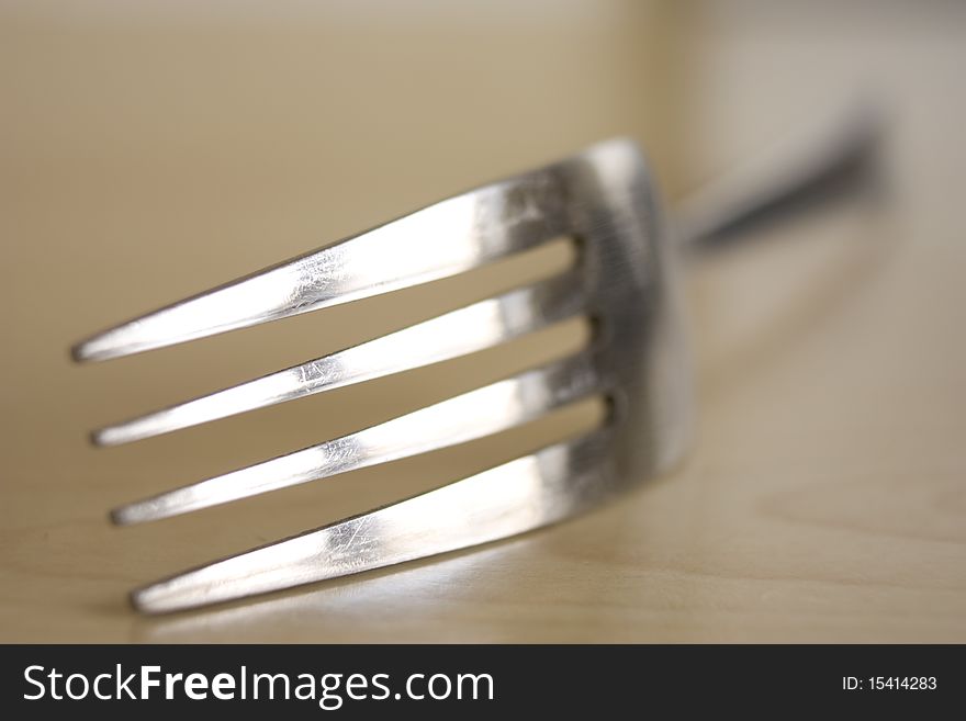 A stainless steel fork placed on a wooden kitchen worktop. A stainless steel fork placed on a wooden kitchen worktop