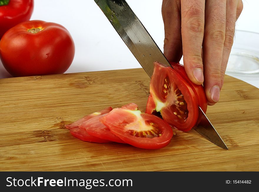 A cook cutting red tomato. A cook cutting red tomato