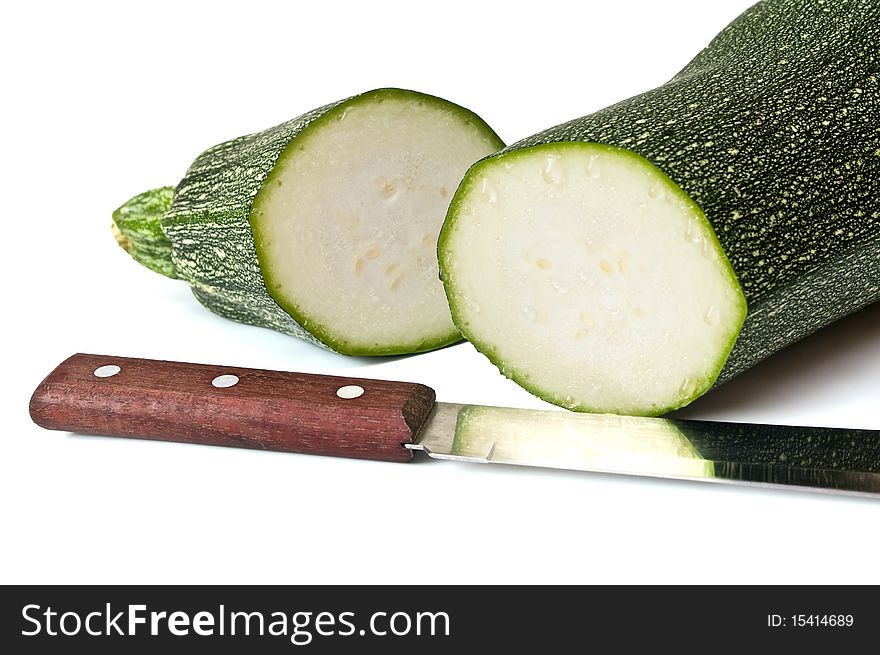 The cut vegetable marrow and knife with reflection on a white background