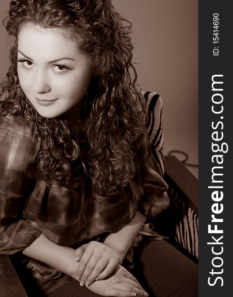 Young and cute caucasian girl with curly hair sitting in striped chair and smiling shot with color correction. Young and cute caucasian girl with curly hair sitting in striped chair and smiling shot with color correction