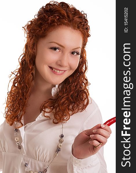 Smiling and happy caucasian red haired girl with curly hair holding chilly pepper and having fun isolated on white background. Smiling and happy caucasian red haired girl with curly hair holding chilly pepper and having fun isolated on white background