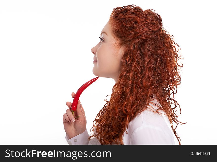 Red haired sensual and beautiful girl with curly hair holding chilly in front of the face and smiling isolated on white background. Red haired sensual and beautiful girl with curly hair holding chilly in front of the face and smiling isolated on white background