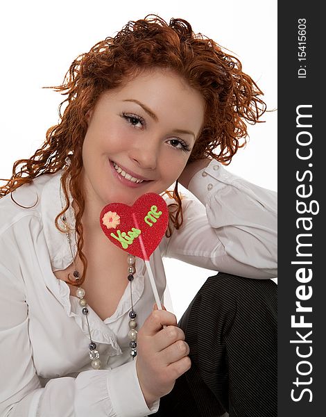 Happy positive looking young caucasian girl with red hair desheveled having fun time with colorful bon-bon sitting isolated over white background. Happy positive looking young caucasian girl with red hair desheveled having fun time with colorful bon-bon sitting isolated over white background