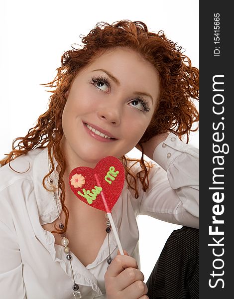 Happy positive looking young caucasian girl with red hair desheveled having fun time with colorful bon-bon sitting isolated over white background. Happy positive looking young caucasian girl with red hair desheveled having fun time with colorful bon-bon sitting isolated over white background