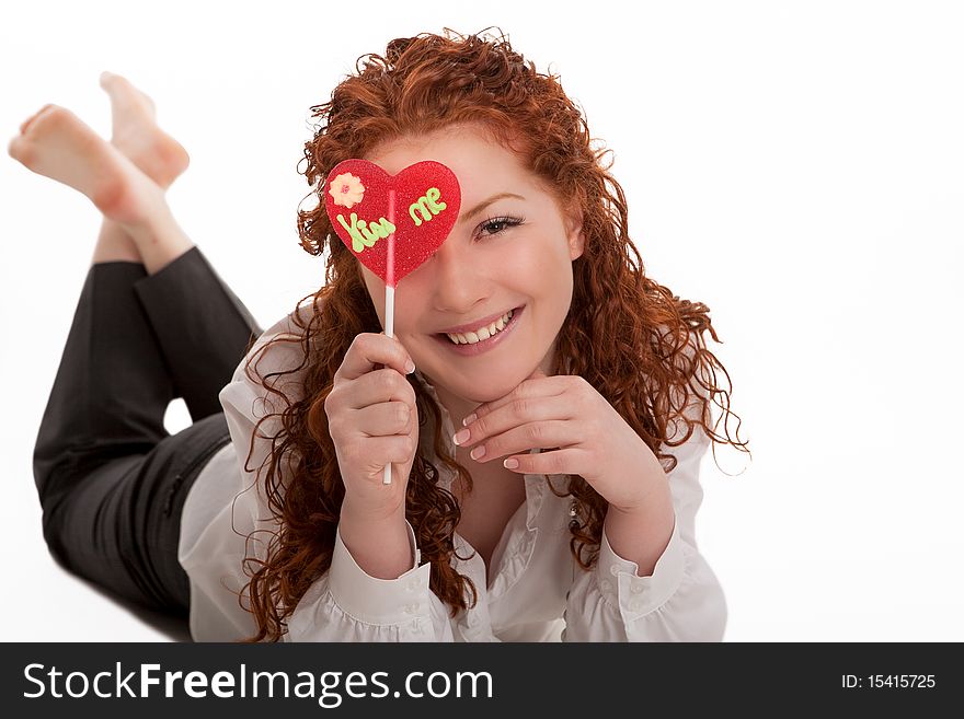 Happy laughing young red haired girl with heart-looking candy lying and relaxing with natural beautiful smile isolated over white. Happy laughing young red haired girl with heart-looking candy lying and relaxing with natural beautiful smile isolated over white