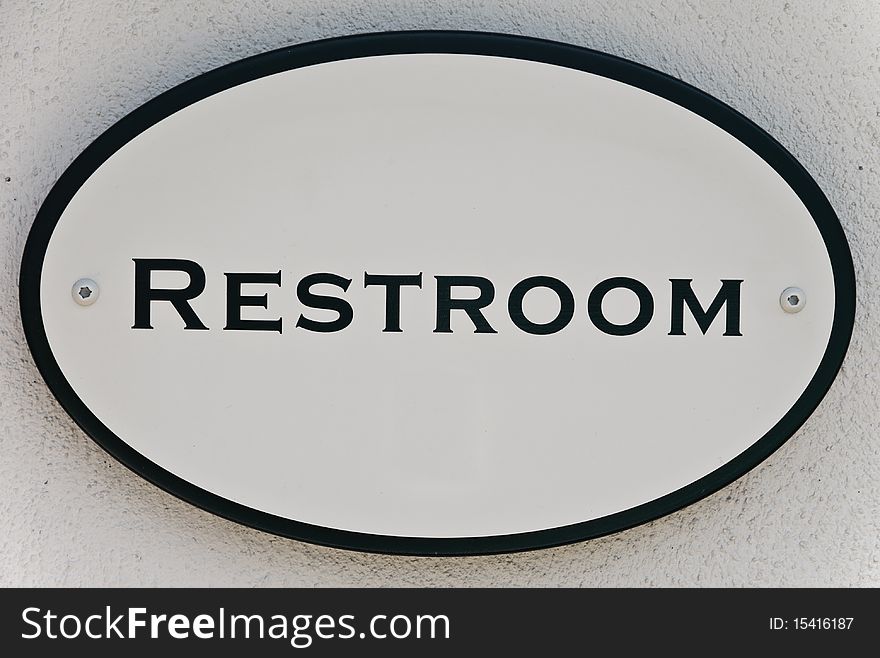 'Restroom' sign on stucco wall