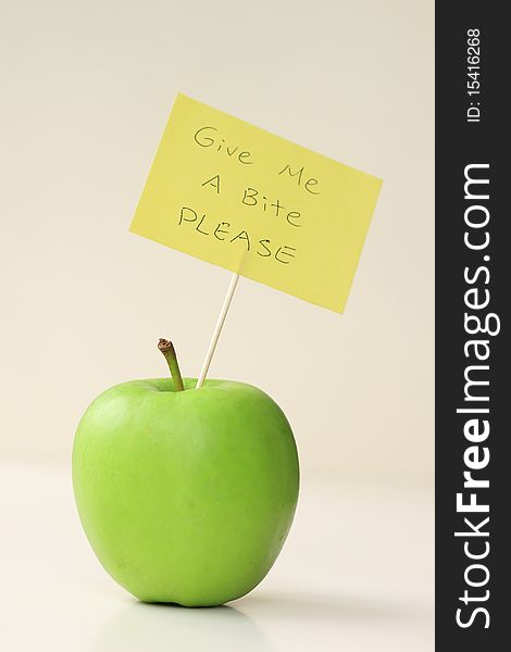 An green apple with a note. Give me a bite please.