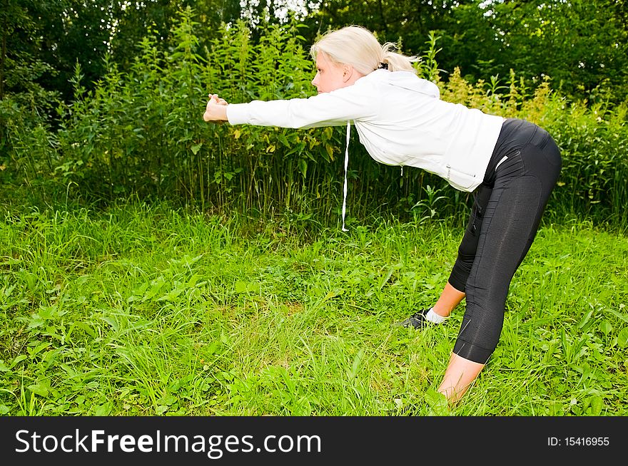 Young blonde woman doing exercises in park. Young blonde woman doing exercises in park