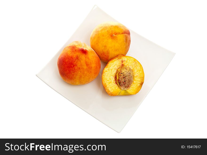 Fresh peaches on a plate. Isolated on white background