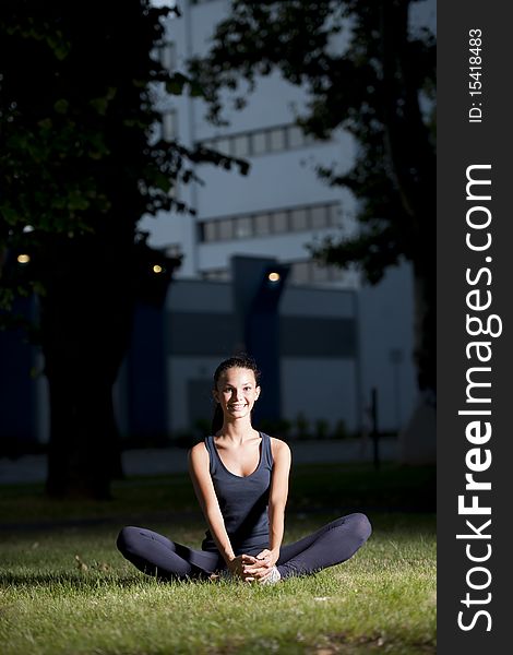 Young woman stretching in grass at evening