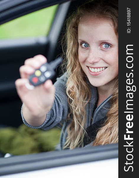 Pretty young woman showing off her brand new car - showing you the car keys. Pretty young woman showing off her brand new car - showing you the car keys