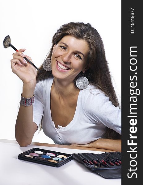 Young brunette smiling makeup artist with brushes and cosmetics