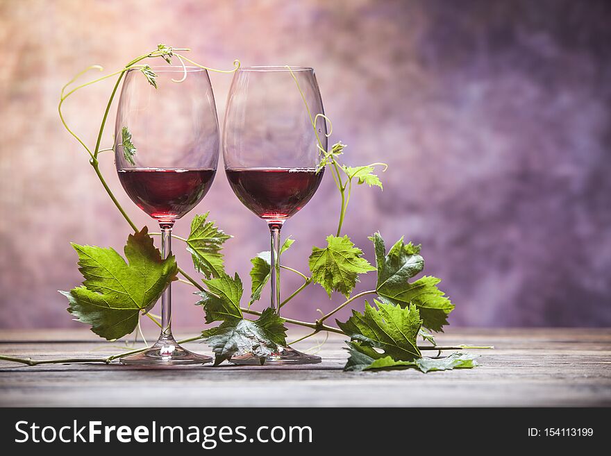 Heart-shaped leaves around two glasses of red wine. Heart-shaped leaves around two glasses of red wine