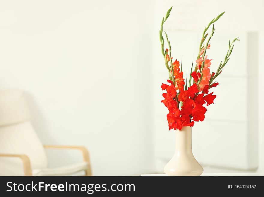 Vase with beautiful gladiolus flowers on wooden table indoors
