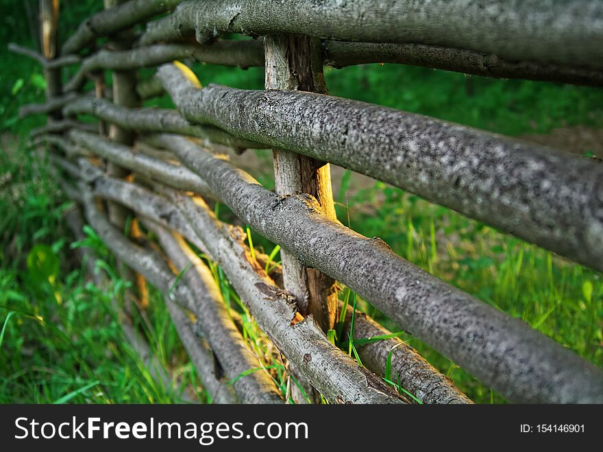 A Fence Woven From Tree Branches In The Evening