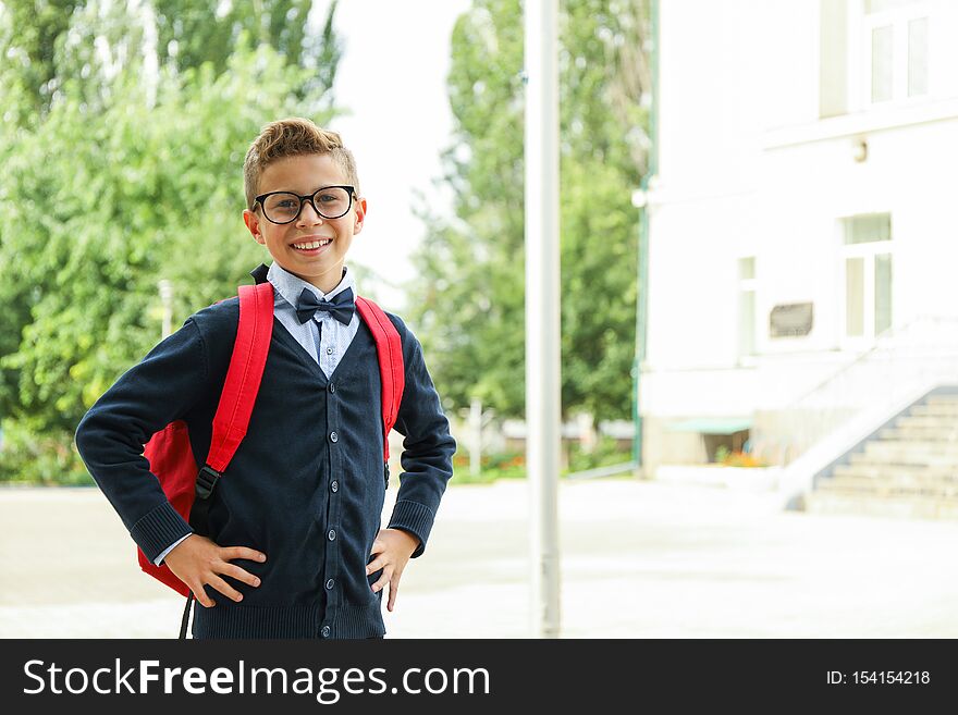 Boy with backpack against school building, space for text