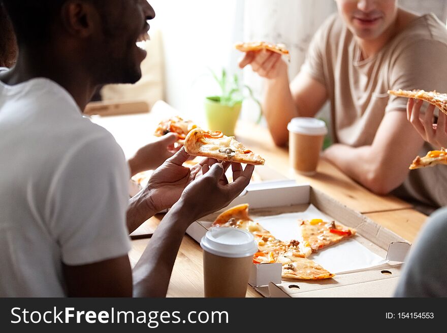 Close up cropped image of diverse friends eating pizza.