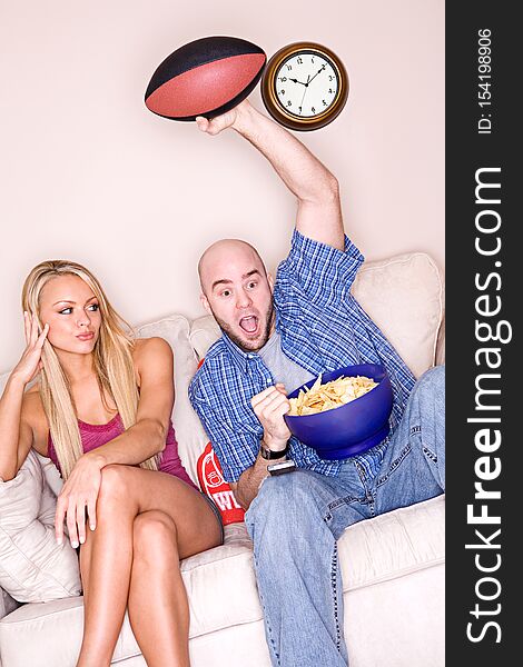 Young couple relaxes on a couch in humorous ways, both in a real setting, and isolated on white. Young couple relaxes on a couch in humorous ways, both in a real setting, and isolated on white