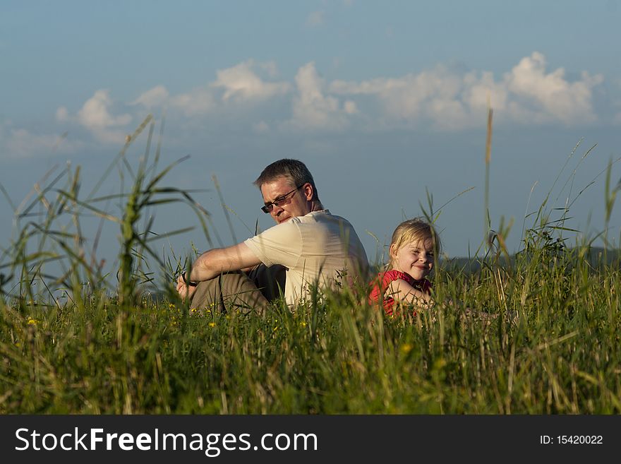 Father With Daughter Sit On Meadow