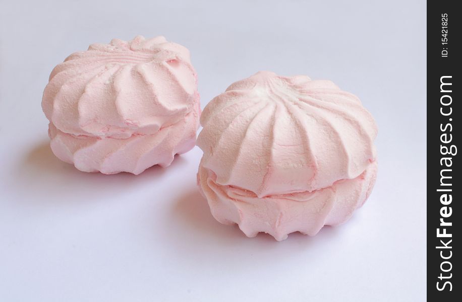 Two soft sweet air of pink marshmallows on a blue background, soft tasty dessert