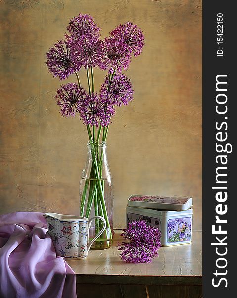 The flowers of bow stand in a bottle, a milkman costs alongside, box with under tea and fabric lies. The flowers of bow stand in a bottle, a milkman costs alongside, box with under tea and fabric lies