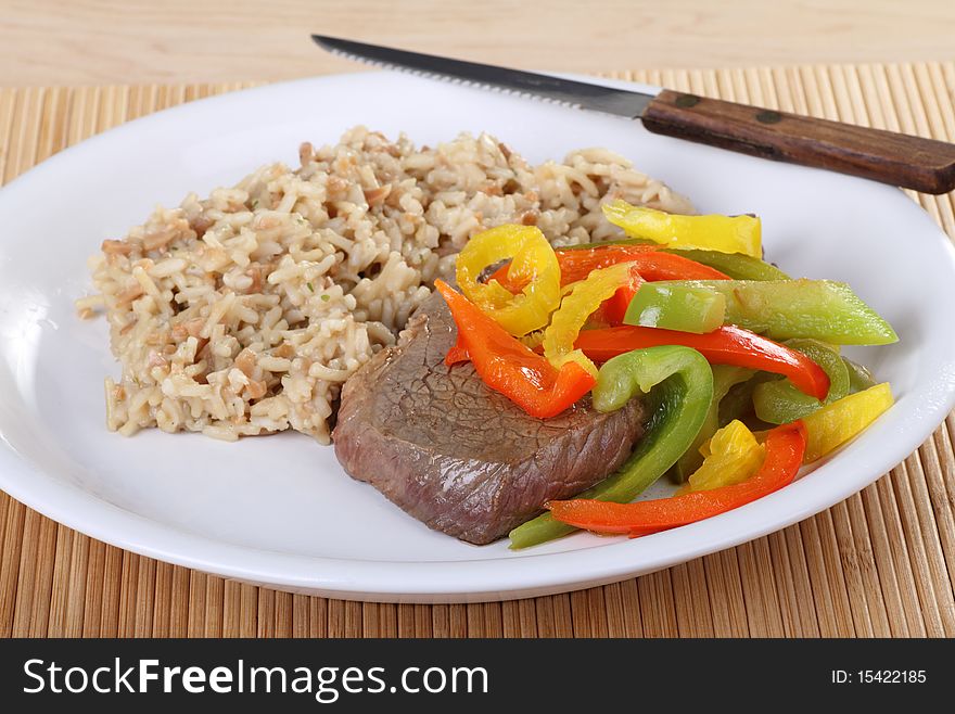 Beef sirloin steak covered with red and green peppers with rice. Beef sirloin steak covered with red and green peppers with rice