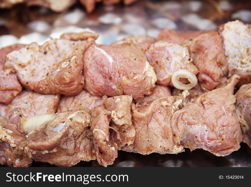 Crude kebab, raw slices of meat stacked on an iron skewer