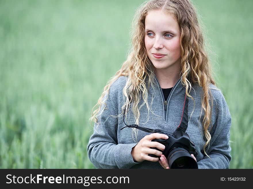 Pretty young woman with a DSLR camera outdoors taking pictures)