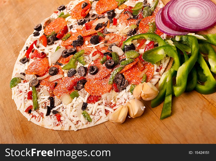 Raw pizza with pepperoni, bell peppers, black olives and onions. Raw pizza with pepperoni, bell peppers, black olives and onions