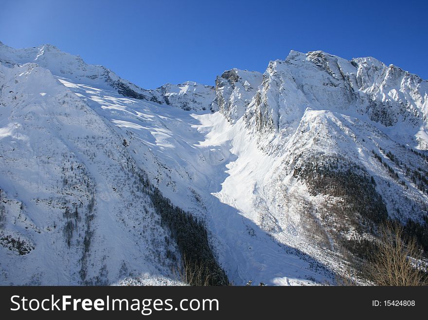 Snowy rocks in sunny weather. Place: Russia, Dombai resort.