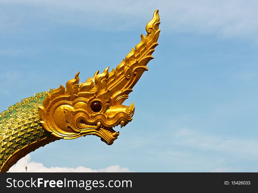Golden Naga or dragon head statue is flying over on the blue sky. Golden Naga or dragon head statue is flying over on the blue sky